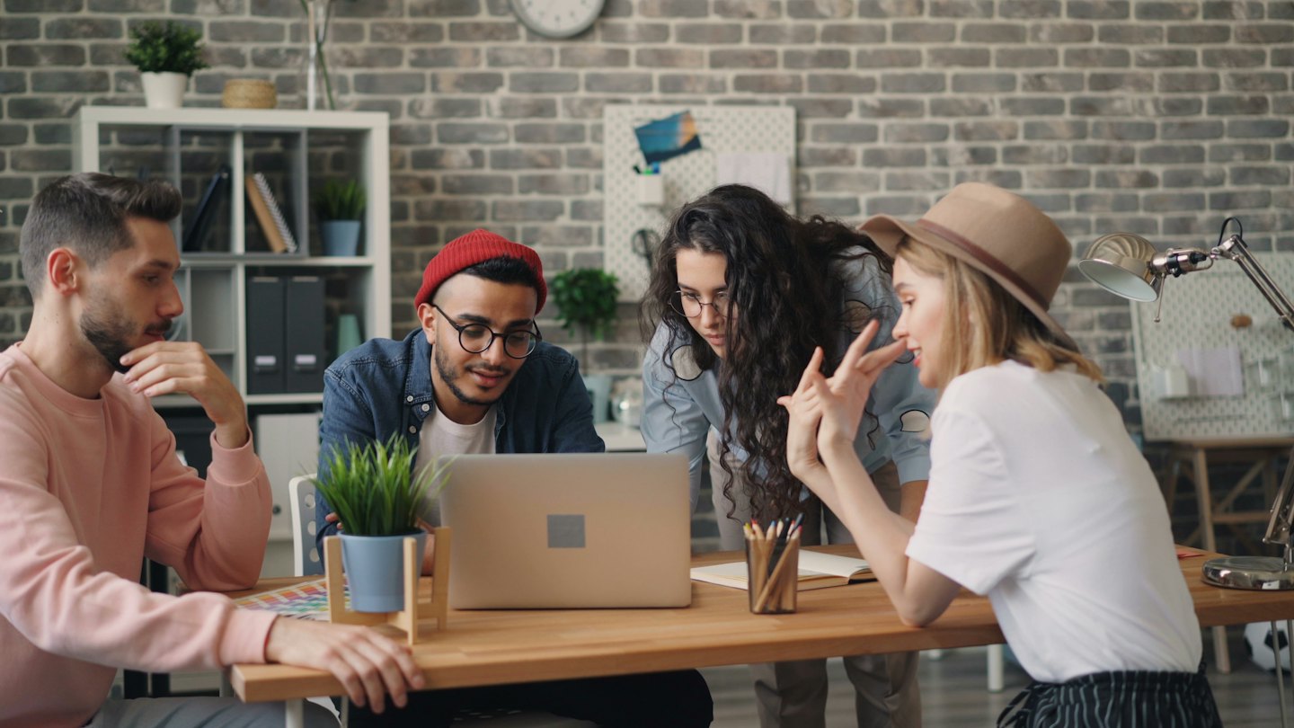 Diverse team collaborating around a laptop in a modern office.